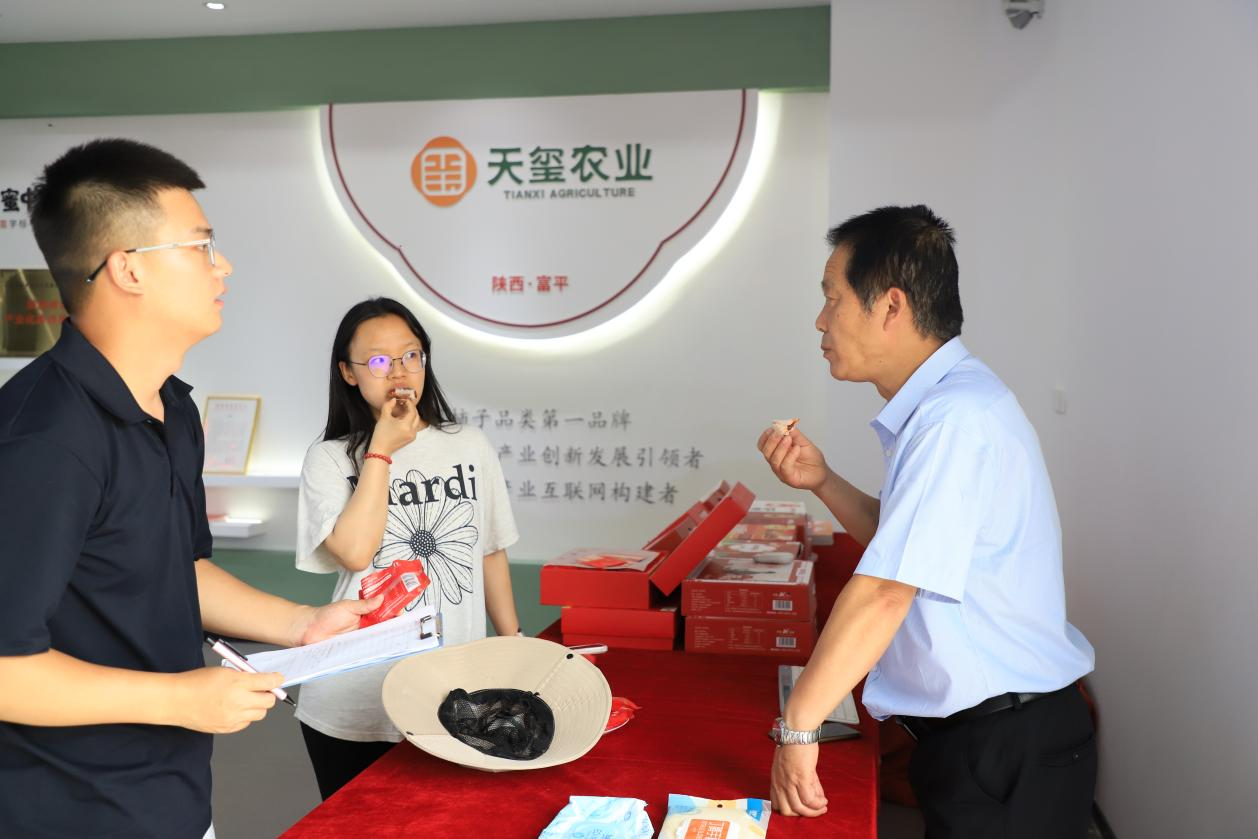 富平大方天玺总经理梁治国（右1）向实践队员王蒙蒙（左1）、李润雨（左2）介绍分发冰柿.png